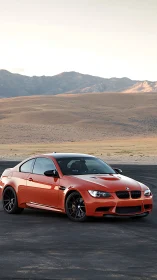 Orange BMW coupe parked on asphalt in open desert landscape