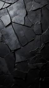 Fractured matte-black slate surface with irregular tectonic seams.