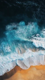 Aerial ocean surf breaking over golden sand shoreline.
