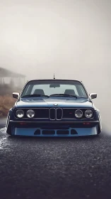 Classic BMW coupe lowered stance on misty open road.