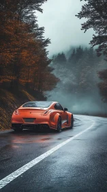 Orange sports coupe on wet forest mountain road in fog.