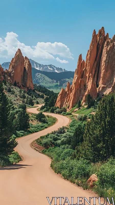Curving dirt road winds toward red rock cliffs and distant peaks.