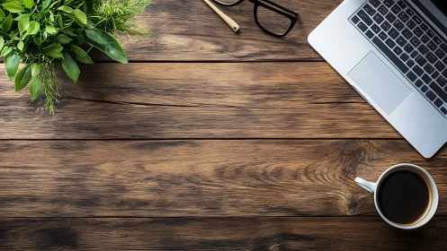 Laptop, coffee and plant on rustic wooden office desk.