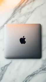 Closed aluminum laptop on marble surface with soft warm lighting