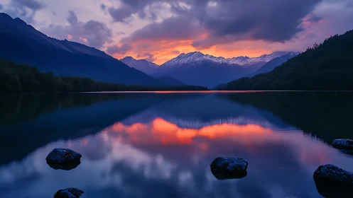 Mountain lake reflects vivid sunset sky with snow peaks