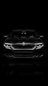 Front view of black BMW sport sedan against black background.