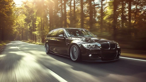 Black BMW touring car driving on a forest highway.