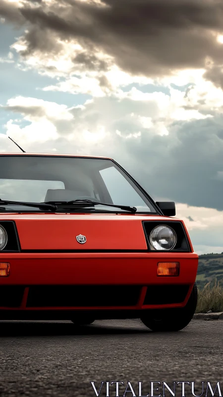 Red vintage hatchback front view under dramatic clouds.