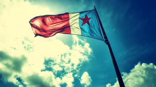 Red and blue flag with central star on tall flagpole in sky.