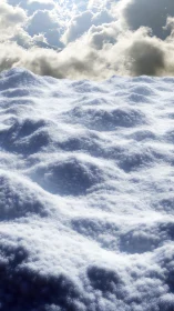 Textured snow surface under bright clouded daylight sky.