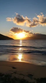 Golden sunset sinks behind distant hills over calm sea