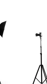 Studio camera and umbrella on minimalist white background.