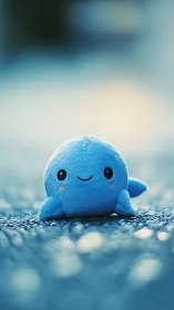 Plush blue whale toy sits on textured surface in bokeh light.