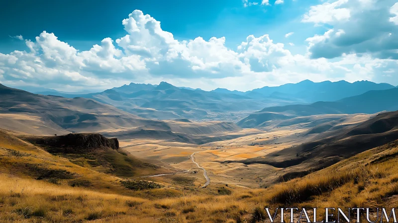 Sunlit mountain valley with winding rural road panorama.