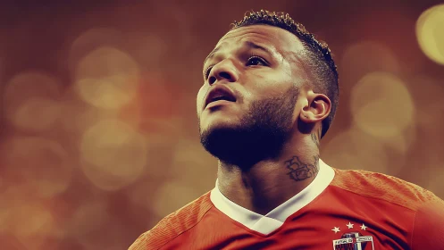 Focused footballer gazes upward under warm stadium lights.