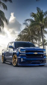 Custom blue Chevy truck with gold rims under palm sky.