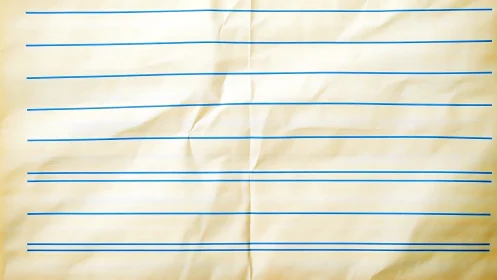 Crumpled primary writing paper with blue ruled lines.