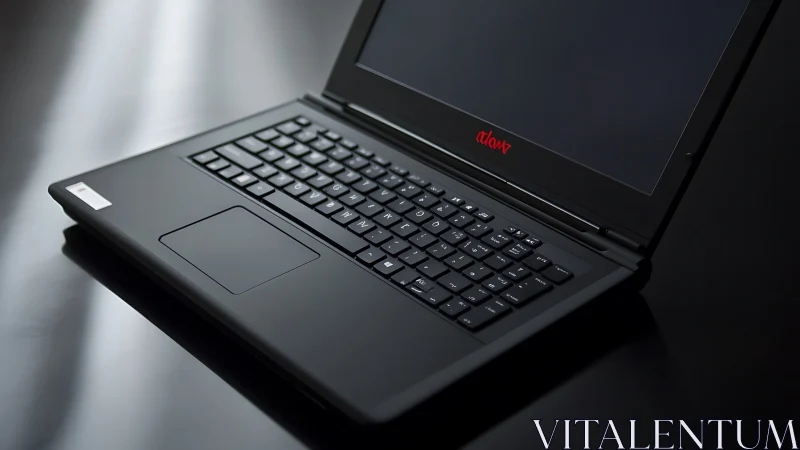 Black laptop computer on reflective dark surface in profile.