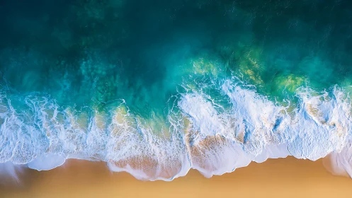 Aerial view of turquoise ocean surf meeting sandy shoreline.