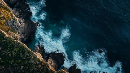 Rocky coastline meets deep blue ocean in dynamic aerial view