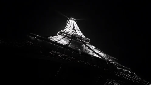 Night upward view of illuminated Eiffel Tower structure.
