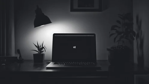 Minimalist monochrome workspace with laptop glow at night.