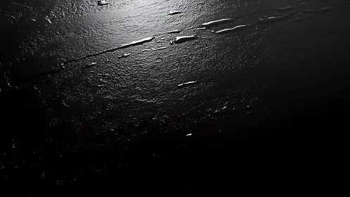 Gleaming streaks across textured black liquid surface.