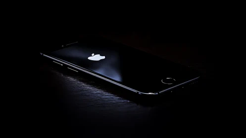 iPhone Device Illuminated Against Black Surface Environment