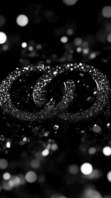 Gleaming intertwined rings in soft black bokeh glow.