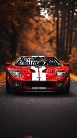 Red sports car with racing stripes on forest road at dusk.