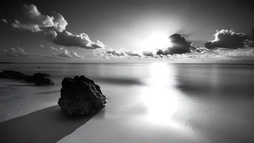 Monochrome seascape records rocks, calm water and low sun