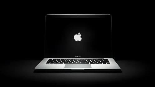 Open MacBook laptop centered against dark black background.