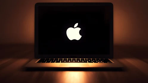 Low-key laptop product shot with luminous central logo focus.