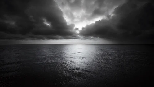 Dark storm clouds over calm monochrome ocean horizon.