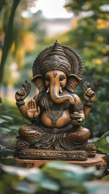Intricate Ganesha statue seated outdoors in soft greenery.