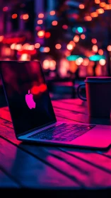 Neon-lit laptop on café table with shallow bokeh field depth.