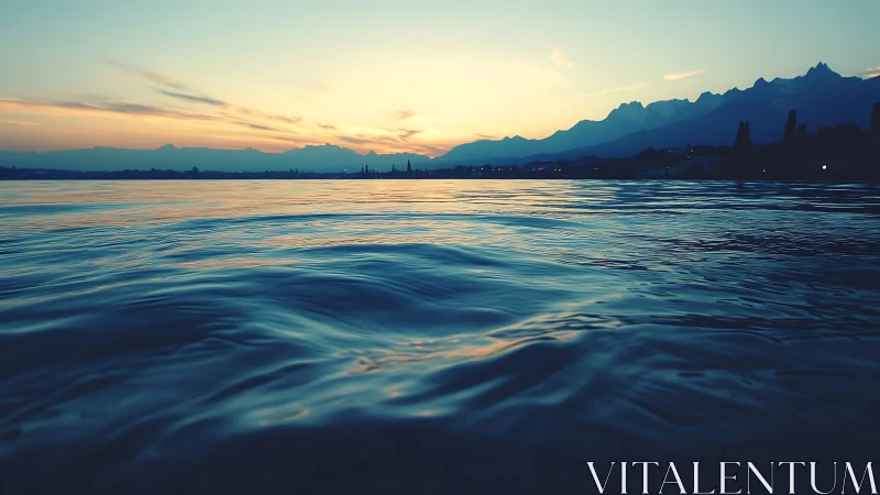 Calm rippling water under distant mountain sunset sky.