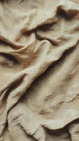 Beige linen fabric forms soft organic folds in macro view.