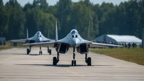 Twin modern jet fighters taxi on runway at airbase.
