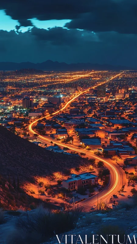 Urban nightscape with winding arterial road and distant hills.