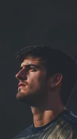 Side-lit portrait captures a thoughtful, upward gaze.