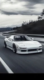 White sports coupe gliding along a moody mountain highway.