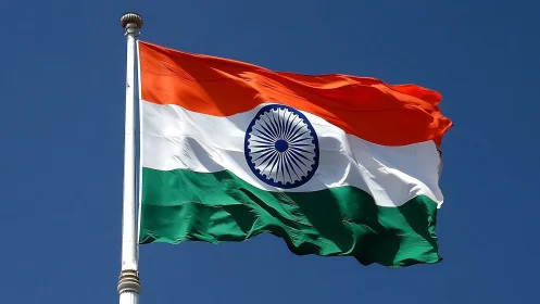 Indian tricolour flag rippling under clear blue midday sky.