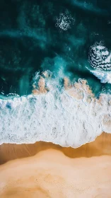 Aerial ocean waves roll onto smooth golden shoreline.
