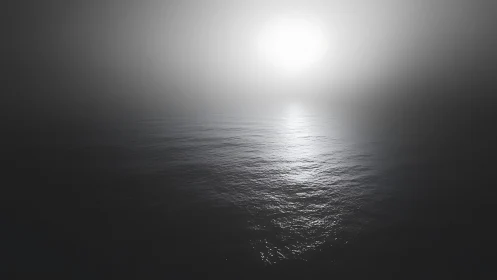 Monochrome ocean horizon glows softly through dense mist