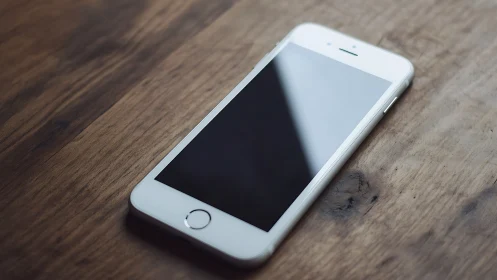 Pristine white smartphone rests on weathered wooden surface.