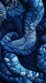 Macro study of densely layered blue embroidery with sculpted relief