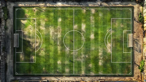 Urban football field from above, worn grass and tiny players.