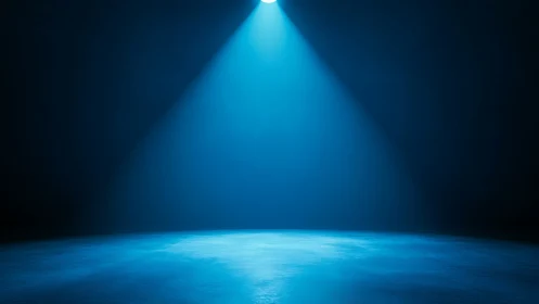Single overhead spotlight illuminates empty blue studio floor