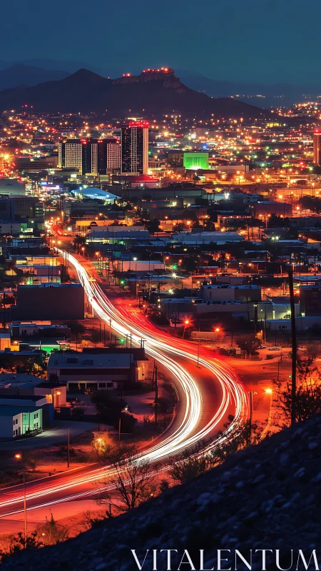 Elevated view of illuminated city and curved traffic trail.